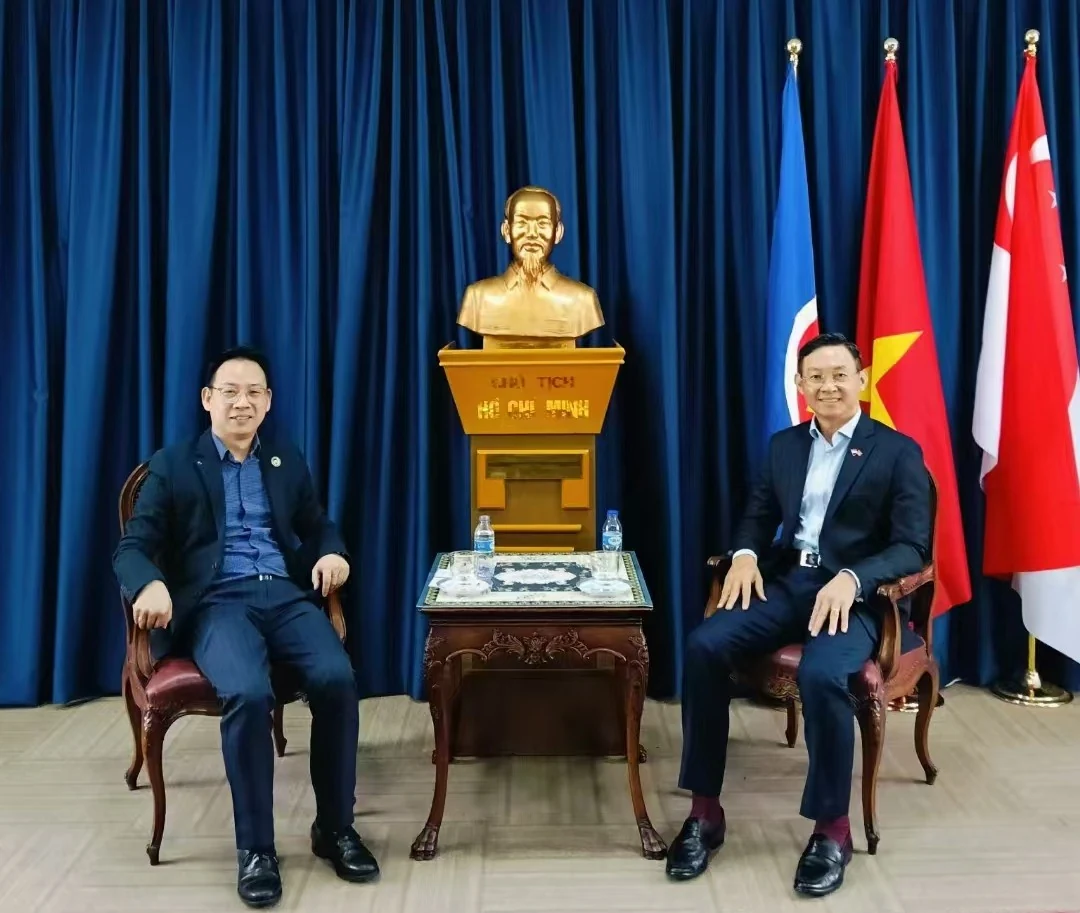 Representatives sit together in the meeting room with Vietnamese and Singaporean flags.