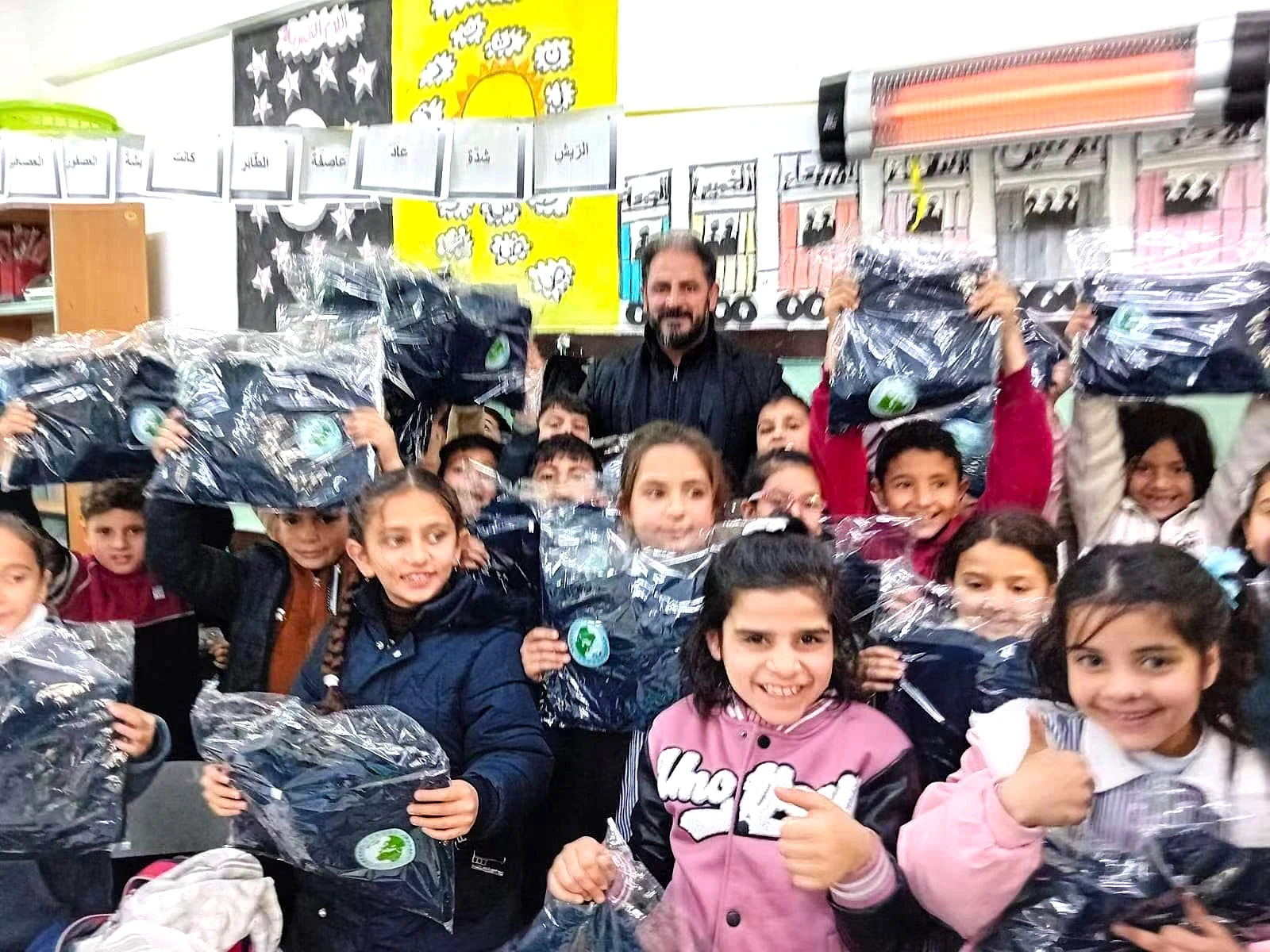 Pupils hold packaged school uniforms in a classroom during the distribution programme.