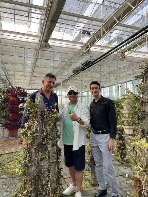 Visitors examine dendrobium plants in the cultivation facility.