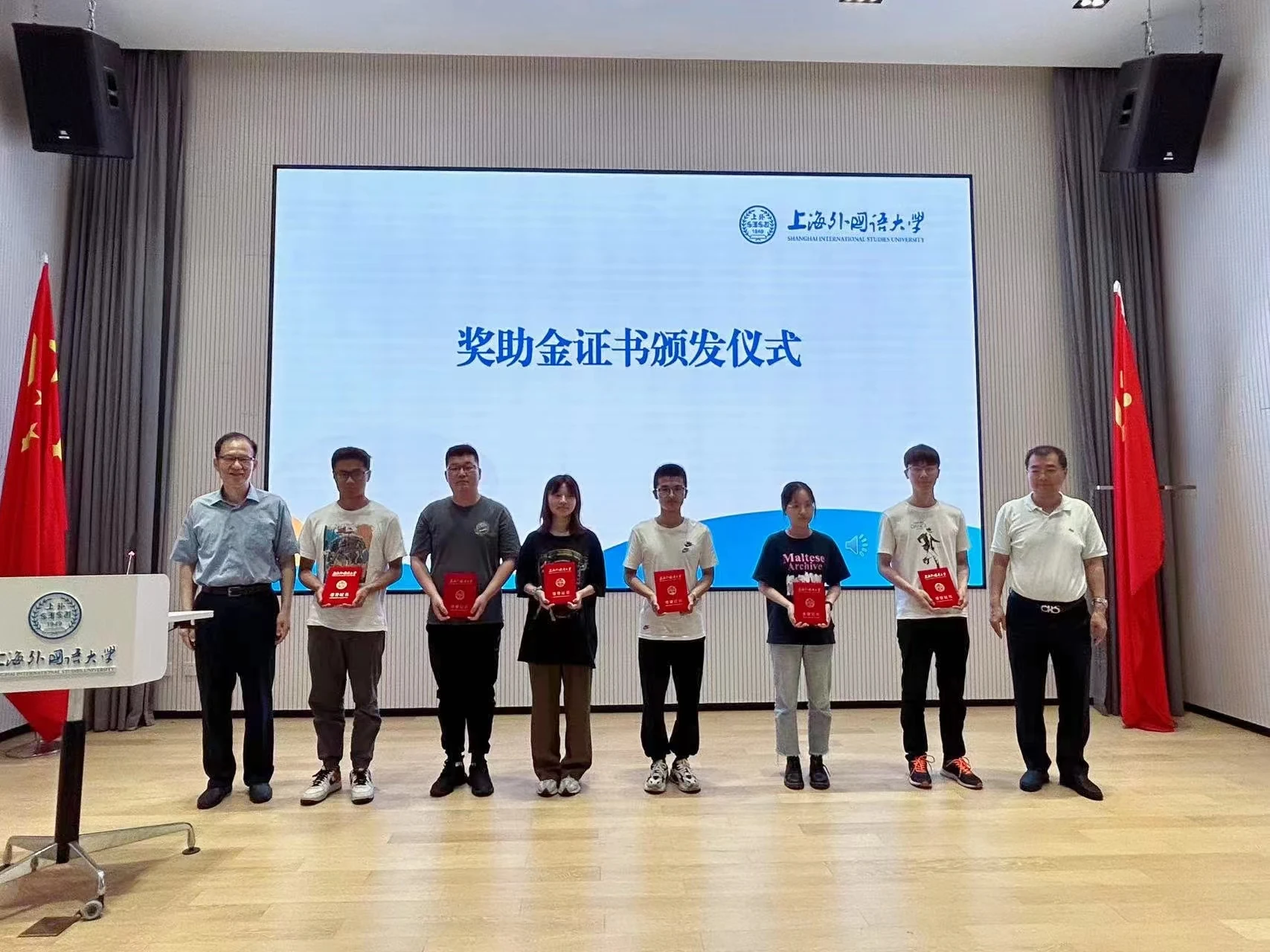Scholarship recipients display their certificates on stage.