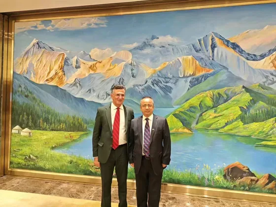 A photograph of two participants in a formal meeting space.
