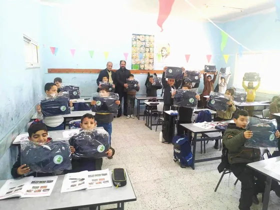 Another classroom photograph records pupils receiving packaged uniforms.