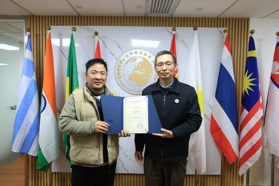 Director He Zairui receives an award certificate from Secretary General Zhang Qi.