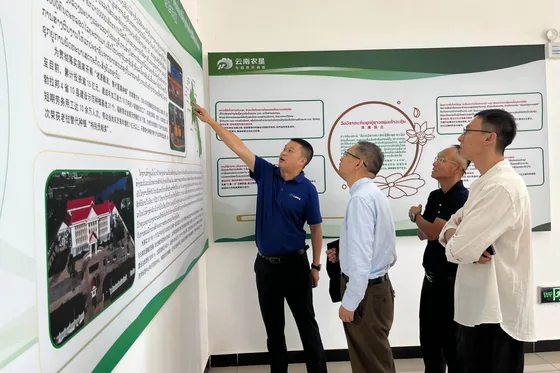 The delegation examines a wall display explaining agricultural cooperation and enterprise activities.