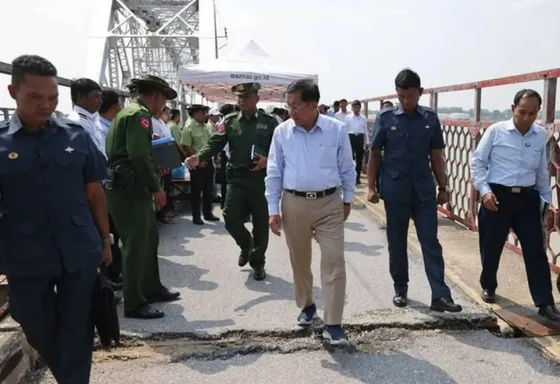 Officials and response personnel walk beside damaged infrastructure in the earthquake-response photograph.
