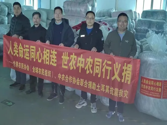 Participants hold a relief banner beside packed blankets and tents.