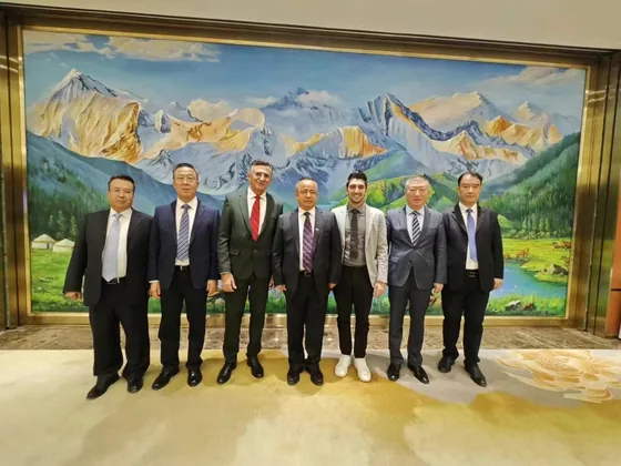 Delegation members gather in front of a mountain-landscape painting.