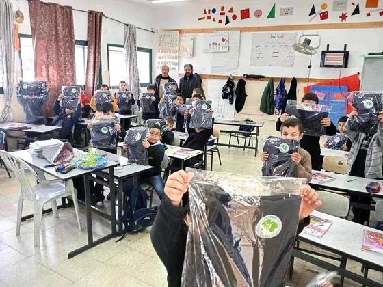 Children display their new uniforms at classroom desks.