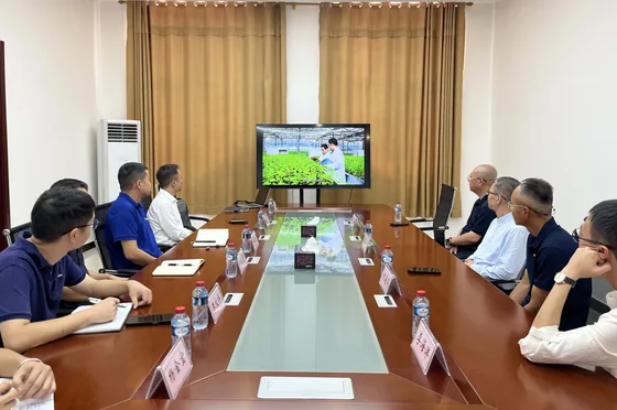 Participants receive an agricultural-enterprise briefing around a conference table.