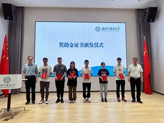 Scholarship recipients display their certificates on stage.